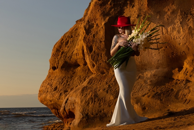 Skaistums vienkāršībā - smilti, kāpa, jūra un sieviete sarkanā cepurē.