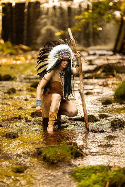 Modele indiāņa tēlā pie ūdenskrituma.